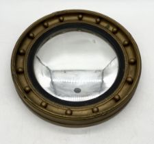 A small circular convex mirror with beaded gilt frame