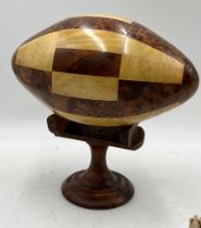 A wooden American football made from various wood types on display stand