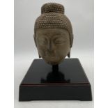 A Chinese carved stone Buddha's head, the hair arranged in a tight curls and rising to a domed unisa