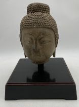 A Chinese carved stone Buddha's head, the hair arranged in a tight curls and rising to a domed unisa