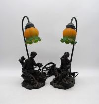 A pair of resin figural table lamps, the bases in the form of a young boy beside a basket of