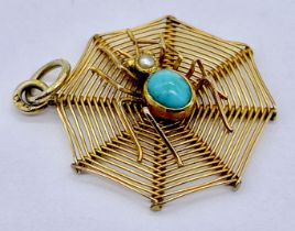 A 9ct gold pendant in the form of a spider on a web set with turquoise and a seed pearl