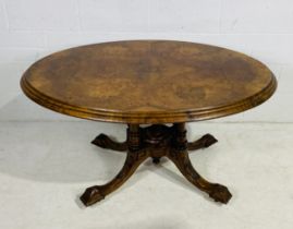 A Victorian walnut oval tip up table on quatrefoil carved legs