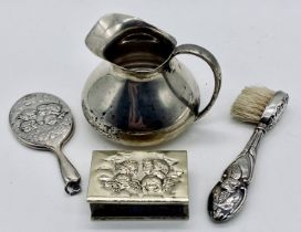 A small hallmarked silver jug, silver matchbox holder, miniature silver mirror and a brush