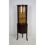 A Georgian style mahogany bow-fronted corner display cabinet, with upholstered interior, raised on