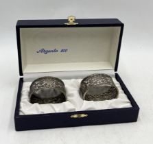 A cased pair of 800 silver serviette rings with pierced foliate decoration