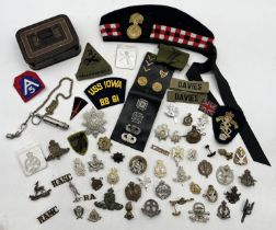 A large collection of military badges including SAS, REME, Royal Scots Fusiliers Glengarry, US