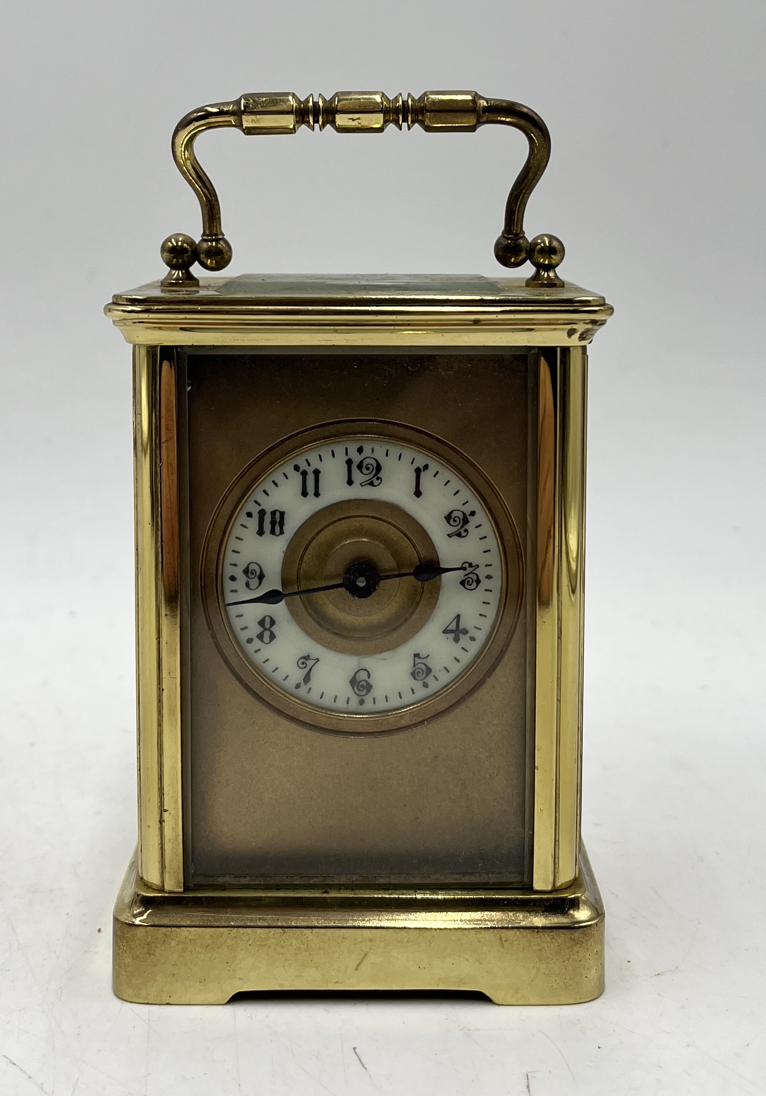 A brass carriage clock with porcelain dial and Arabic numerals