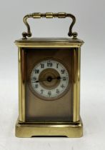 A brass carriage clock with porcelain dial and Arabic numerals