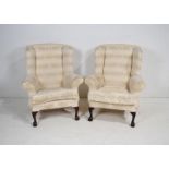 A pair of white upholstered wingback armchairs, raised on claw and ball feet