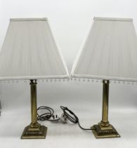 A pair of brass column table lamps with shades