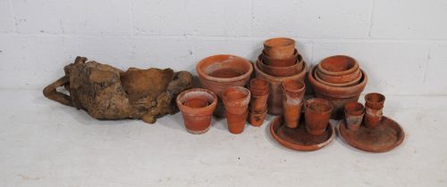 A quantity of various sized terracotta garden plant pots, along with a large wooden root burr