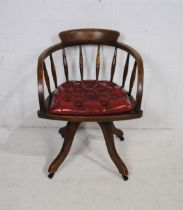A 20th century oak swivel office chair, with turned spindle back and red leather seat with button-
