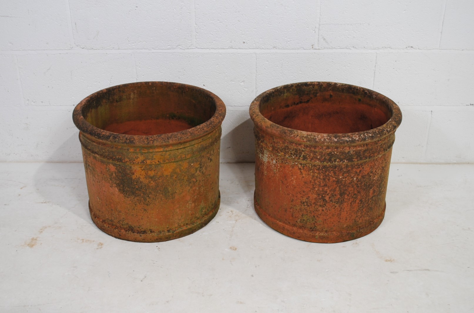 A pair of large weathered terracotta garden pots of cylindrical form - diameter 50cm, height 39cm