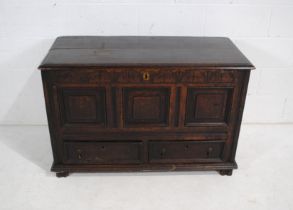 An antique oak mule chest, with carved decoration and panelled detailing, with two drawers under -