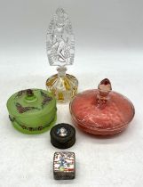 An assortment of powder puffs, a scent bottle with nude figurine, a trinket box with hand painted