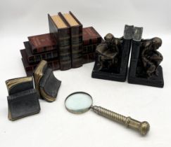 Three sets of bookends in various forms along with a large brass handled magnifying glass