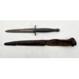 A World War II style Fairbairn Sykes commando dagger with ribbed handle and leather sheath