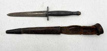 A World War II style Fairbairn Sykes commando dagger with ribbed handle and leather sheath