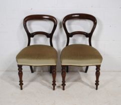 A pair of Victorian mahogany balloon-back chairs, with upholstered seats and carved decoration,