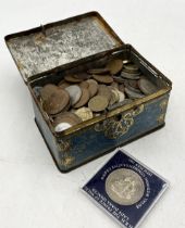 A collection of various coinage in vintage Lyon's tea money box