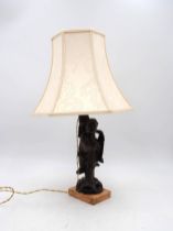 A Chinese table lamp, in the form of a carved wooden elderly man, on marble base, with shade