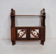 A turn of the century mahogany small wall hanging cupboard, with Mintons tiled doors and pierced