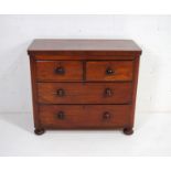 A Victorian mahogany chest of four drawers, with turned handles, raised on flattened bun feet -