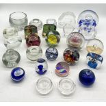 A collection of glass paperweights, candle holders, inkwells etc. over three shelves.
