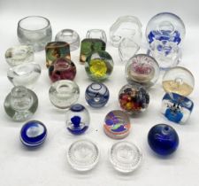 A collection of glass paperweights, candle holders, inkwells etc. over three shelves.