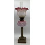 A Victorian oil lamp with cranberry glass shade (chip to base of shade)