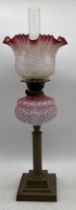 A Victorian oil lamp with cranberry glass shade (chip to base of shade)