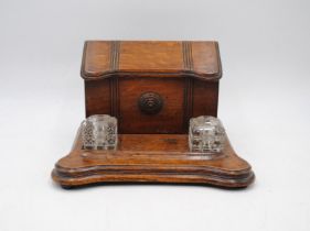 An antique oak stationary stand, with two glass inkwells and pen recess