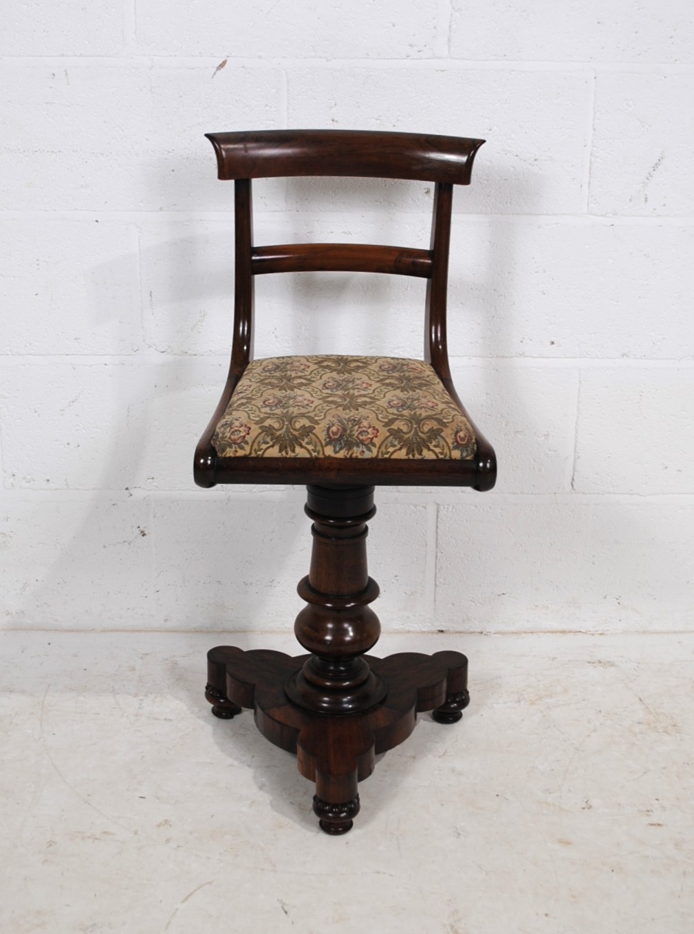A Victorian rosewood harpists stool, with rotating upholstered seat, raised on turned trefoil base