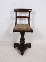 A Victorian rosewood harpists stool, with rotating upholstered seat, raised on turned trefoil base