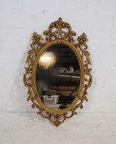 An ornate gilt framed oval wall mirror - 90.5cm x 56.5cm
