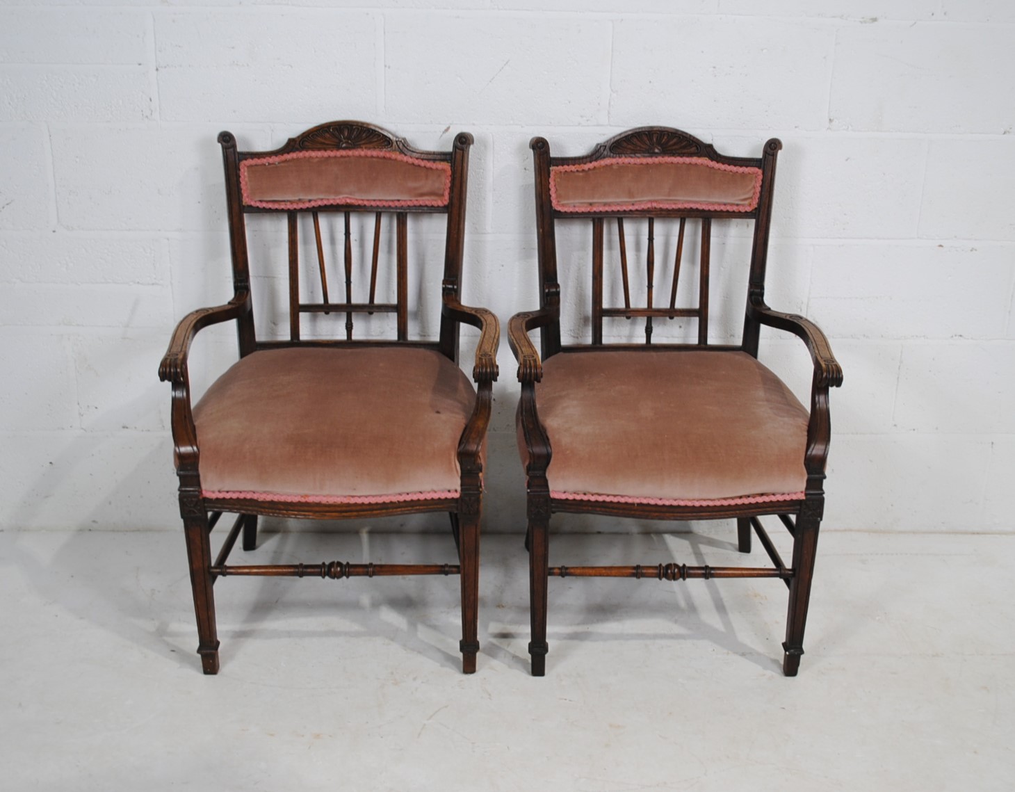 A pair of upholstered oak carver chairs, with carved detailing, raised on tapering legs