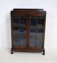 A 20th Century oak display cabinet, with three shelves. raised on ball feet - length 88cm, depth