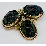 An antique unmarked yellow metal brooch set with 3 iridescent scarabs