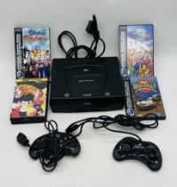 An unboxed Sega Saturn computer console with two controllers and three games etc - no power supply