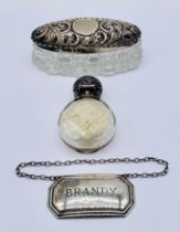 A small silver topped scent bottle, silver topped dressing table pot and a bottle label