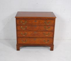 A walnut veneered chest of four drawers of small proportions, with brush slide, raised on bracket