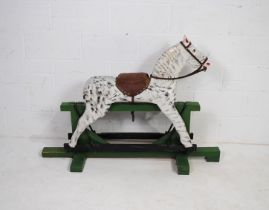 A vintage painted wooden rocking horse, with leather saddle - length 137cm, depth 98cm