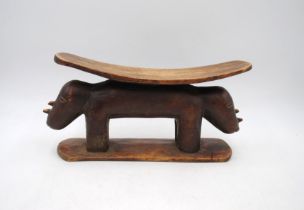 A carved wooden tribal headrest, in the form of rhinoceroses - length 34cm