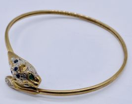 A tested 9ct gold bangle in the form of a leopards head set with diamond, emerald and sapphire,