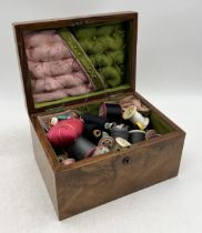 An antique walnut sewing box with numerous threads, pincushions etc.