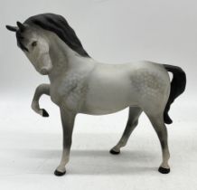 A Beswick dapple grey horse with head tucked and front leg raised in bisque finish