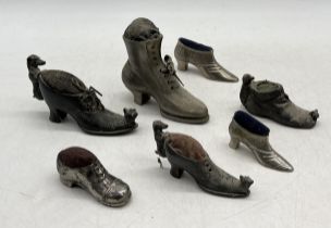 A collection of silver plated pin cushions in the form of boots and shoes