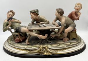 A 20th century Capodimonte porcelain figure, The Cheats, modelled by B.Merli, raised on an oval