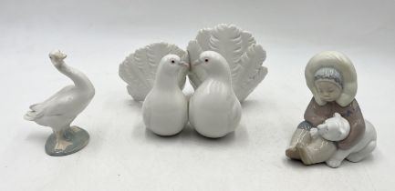 A collection of three Lladro figures including Eskimo playing with polar bear cub, pair of doves and